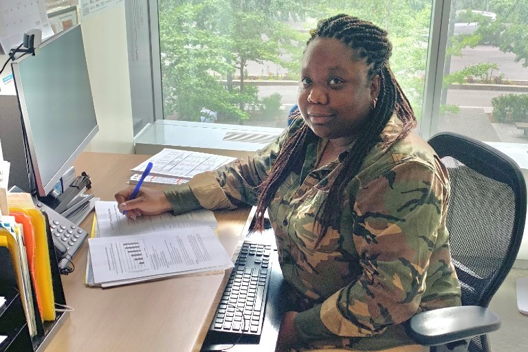 Shanika Taylor-Haughton: “My apprehensions subsided when I learned about the policies put in place by Health Services.” A woman sits at a desk with a pen in hand and papers with charts in front of her.
