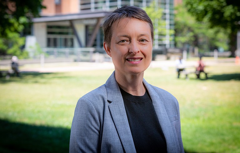 Shannon Lloyd: “You can’t make these decisions in isolation, thinking only about the specific problem you’re trying to solve — you have to look at the entire system.” Woman with short, blonde hair, a black top and grey suit jacket