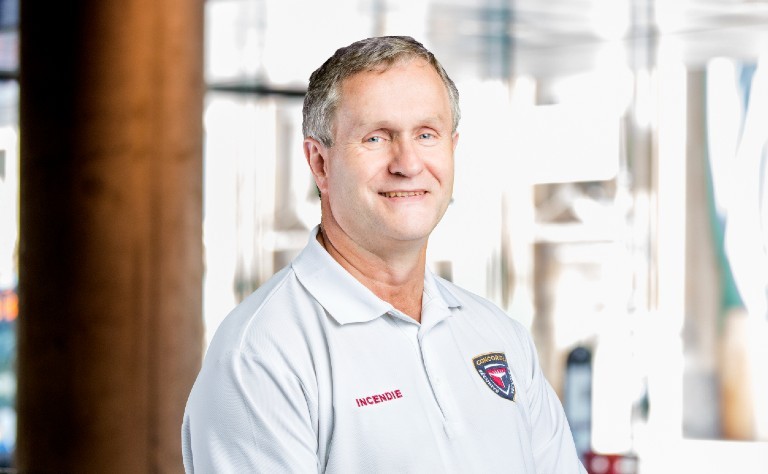 Smiling man wearing light-blue collared polo with Concordia logo and "Incendie" in red font