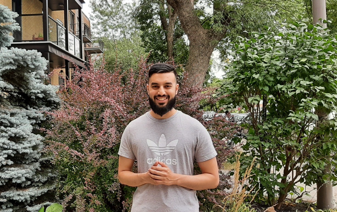 Nabeel Chaumun stands on a lawn in front of trees