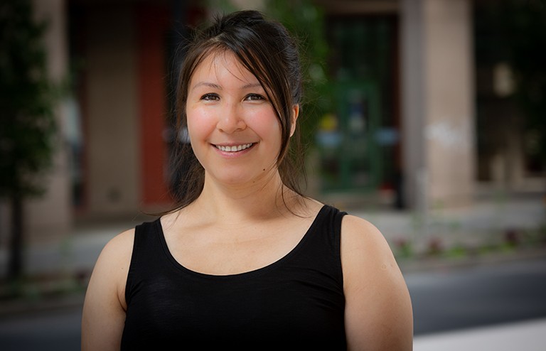 Adamina Partridge: “It was important that I connect with community to help guide me through my studies.” Young, Indigenous, smiling woman with long dark hair and a black top.