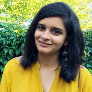 Young woman with long, dark hair and a yellow shirt.