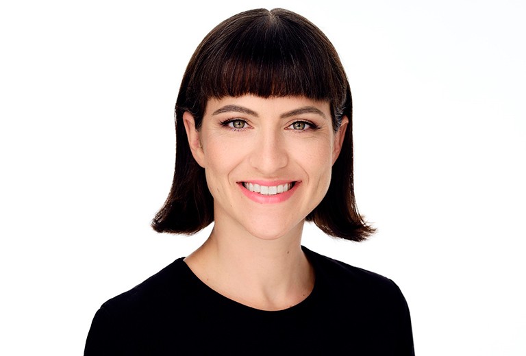 Smiling woman with shoulder-length dark, straight hair and a black top.