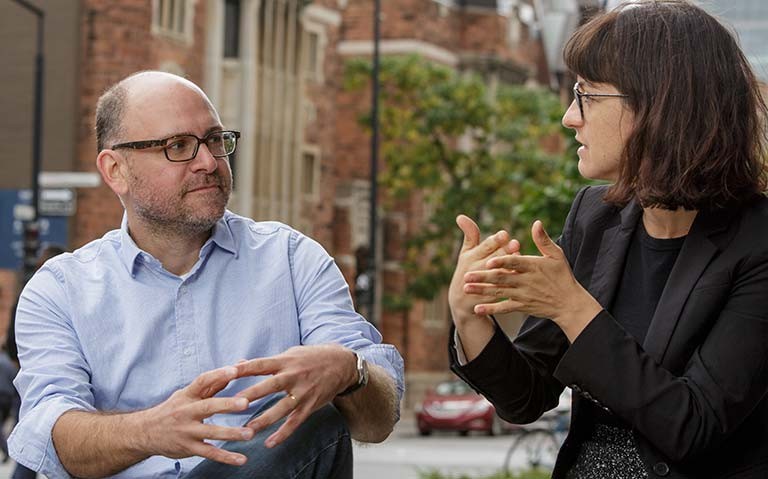 A man and a woman engaged in conversation in an outdoor setting.