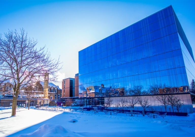 Modern multi-level rectangular building reflecting its surrounding winter landscape
