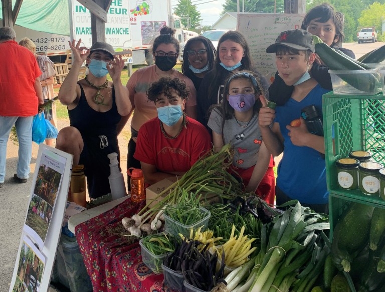 Young Roots City youth standing behind a table with fresh produce