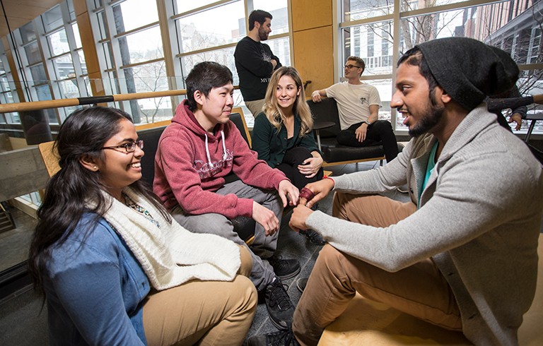 A group of young university students sitting around talking together.