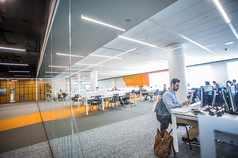 People sitting at desks with computers in a library setting