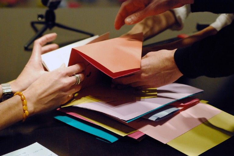 PME-ART, Adventures can be found anywhere, même dans la mélancolie, 2014. Photo: Mathieu-Chartrand Two sets of hands sifting through colourful paper on a table