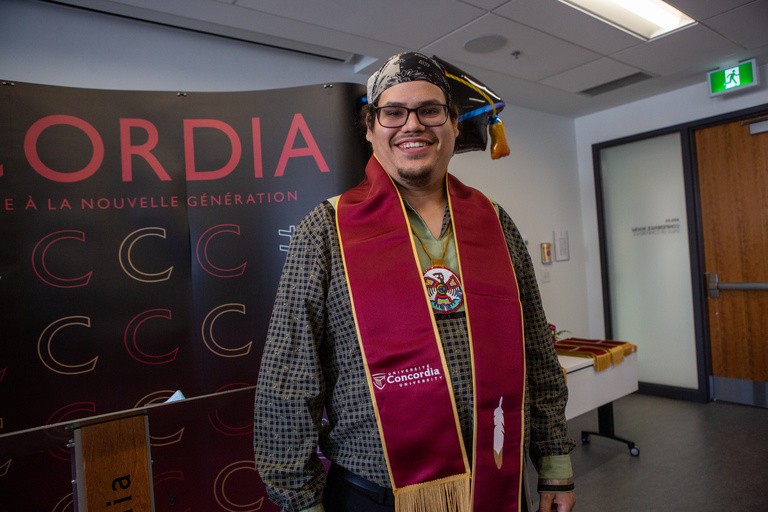 A man poses for a graduation photo.