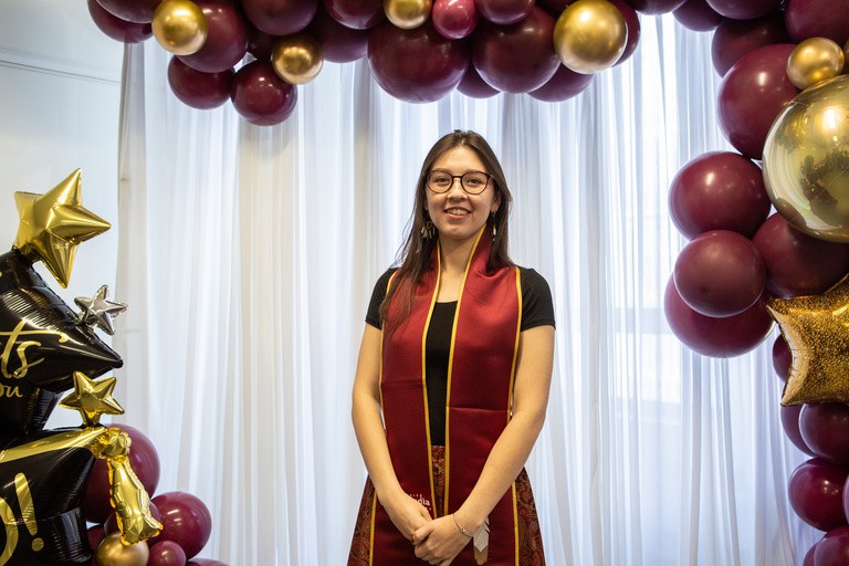 A woman poses for a graduation photo.