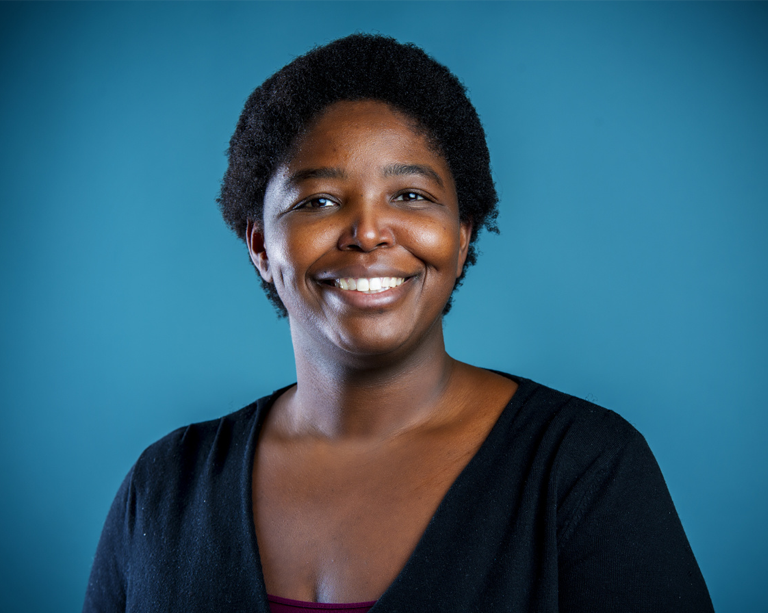 A smiling woman in front of a blue background.