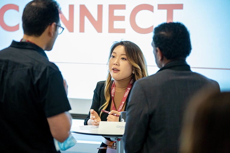 Young Asian woman talking to two men at an event.