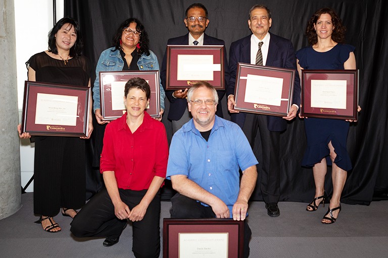 A group of diverse people holding award plaques and smiling for the camera