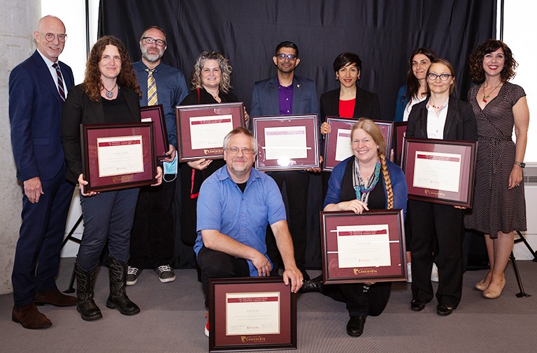 A group of diverse people holding award plaques and smiling for the camera