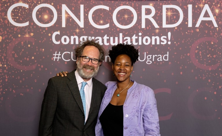 Man wearing blazer with sky-blue tie and woman wearing lilac blouse and blue necklave and earrings