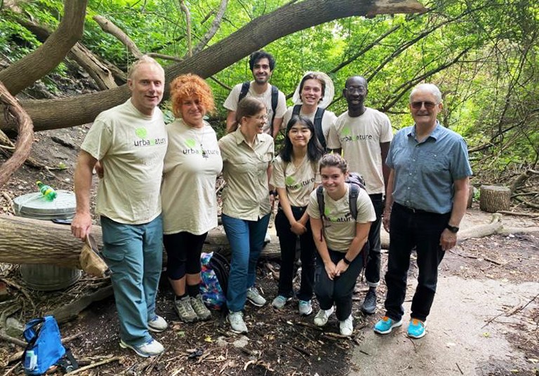 A group of men and women standing together for a photo in an outdoor, forest setting