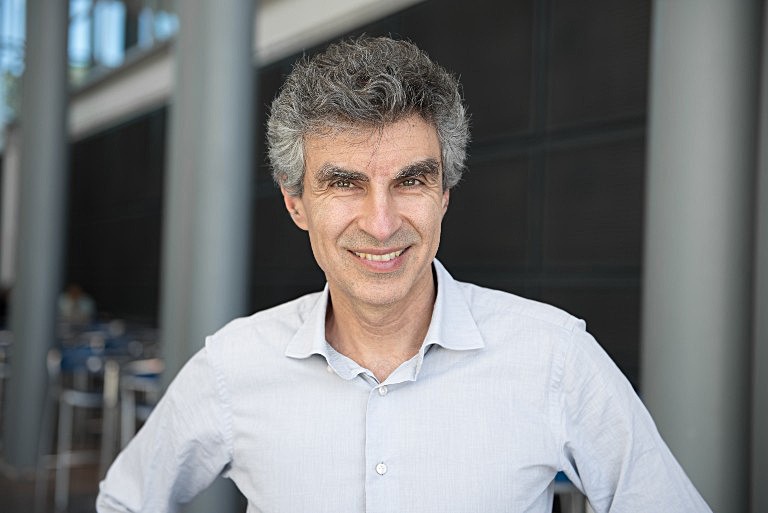 A smiling man standing in front of a grey building