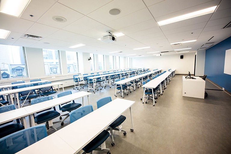 An empty classroom in a university, with row desks and accompanying chairs