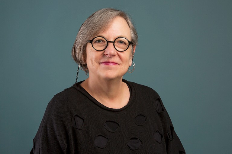 Smiling woman with black-rimmed glasses, a bob haircut and wearing a black top.