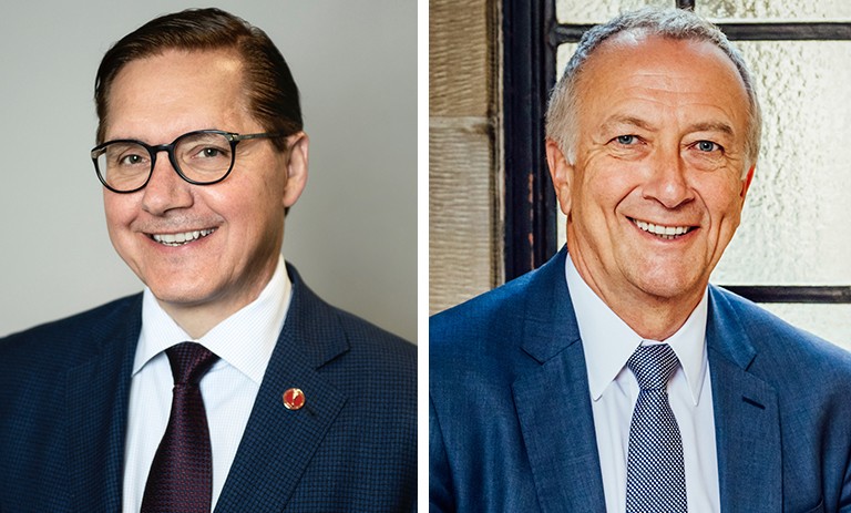 Two older smiling men wearing suits and ties.