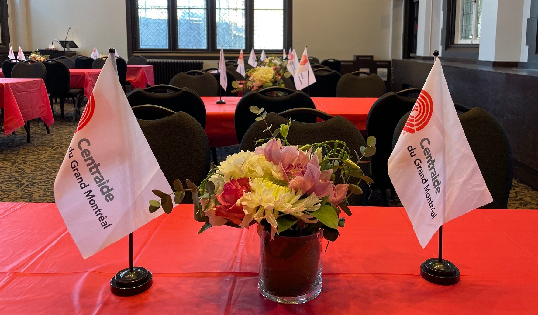 Two Centraide flags sit on a table with a bouquet of flowers in between them.