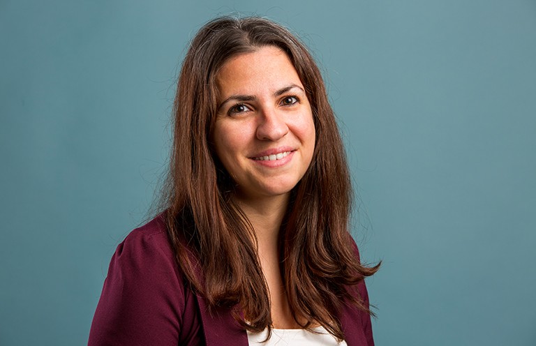 Savvy Papayiannis: “It’s an exciting time because we’re moving away from the pandemic with all the lessons and tools we’ve developed.” Smiling woman with long, dark hair, wearing a white top and a burgundy blazer.