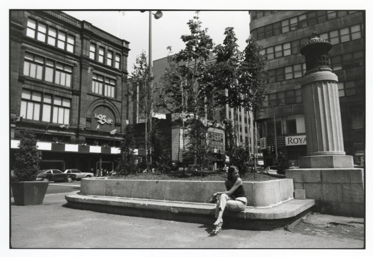 Woman seated on concrete bench in city square