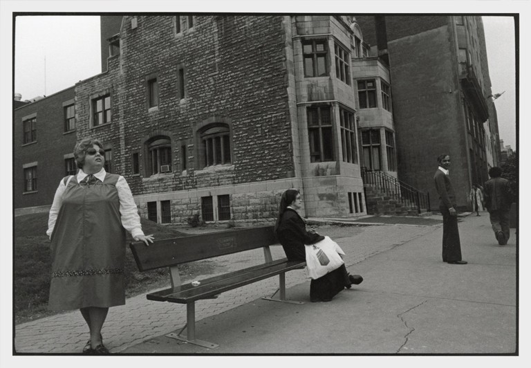 Montreal, 1978 A woman leans against a bench that a nun is sitting on. An old building sits in the background.