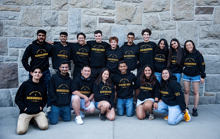 Charlene Gail Baay: “Seeing everyone working together will be extremely fulfilling.” A group of smiling young people in black hooded sweatshirts that have the words "HackConcordia" in yellow writing on the front.