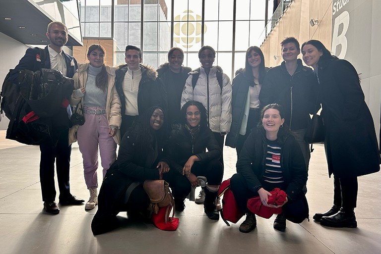 A group of several people standing together in an interior and smiling for the photographer.