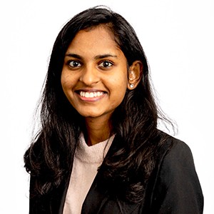 Young smiling woman with long black hair and wearing a pink top and black blazer