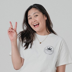 Young woman smiling widely wearing a white T-shirt and doing a peace sign