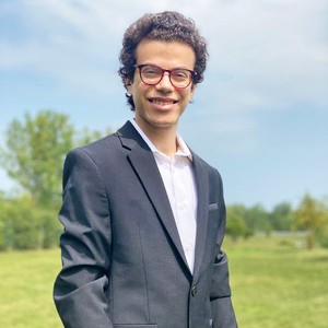 Smiling man with dark hair, glasses and wearing a suit shirt and jacket