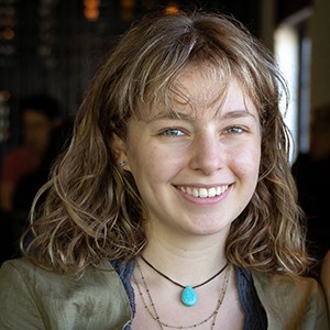 Young smiling woman with long blonde hair, wearing a turquoise necklace