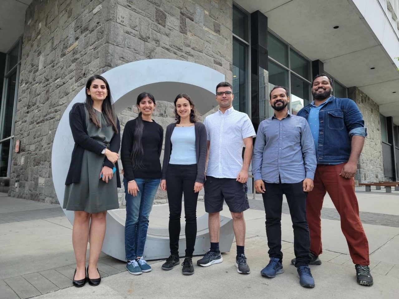 Group of students standing outside behind a large C