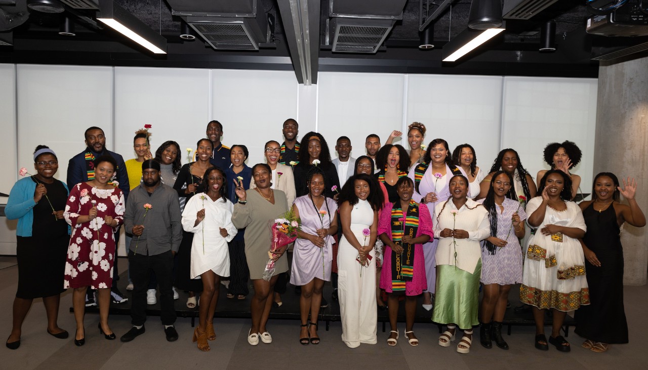 A group of more than 20 people gathered in a room, smiling at the camera