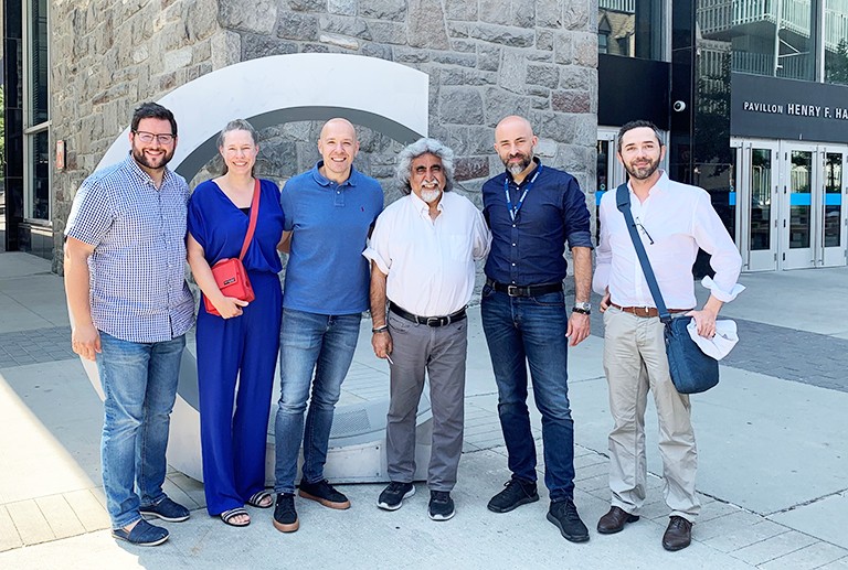 A group of men and women standing together in a line on a city sidewalk and smiling for the camera