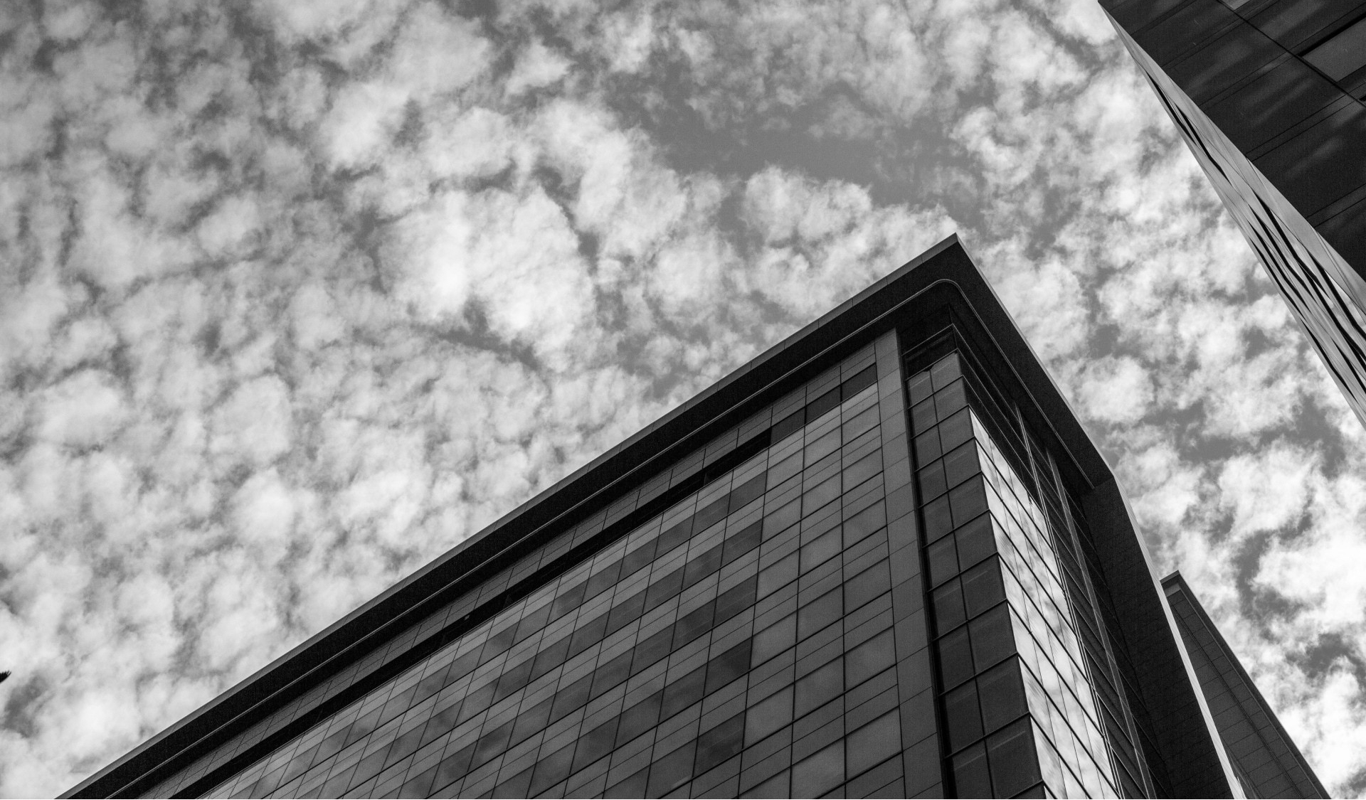 A black and white shot of a cloudy sky and buildings