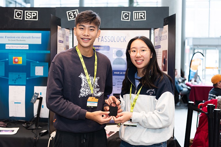 From left: Alexander Wang and Wendy Wen. A young man and woman standing in front of a science project and holding a large black lock