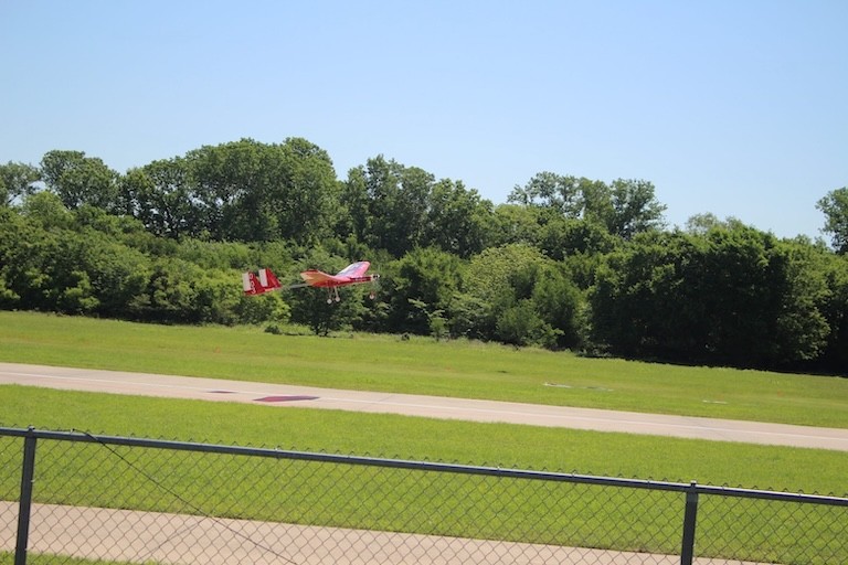 Two small aircraft sitting on a runway with an award plaque in front of them.