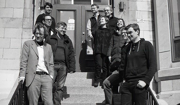 Gregory Lavers, bottom right, is pictured with the Department of Philosophy faculty and student representatives in 2016-17. | Photo by Rohan Quinby A black and white image of a group of people gathered on some outdoor steps.