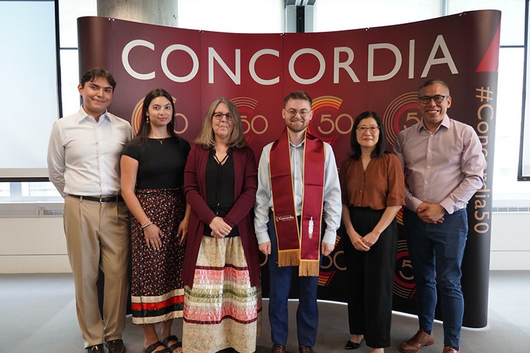 Aidan Tecumsah Condo: “I knew if I’m going to be representing Indigenous Peoples, I wanted to get a better grasp on other Indigenous cultures and their ways of life.” A group of people, one of them wearing a convocation sash, standing and smiling for the camera.