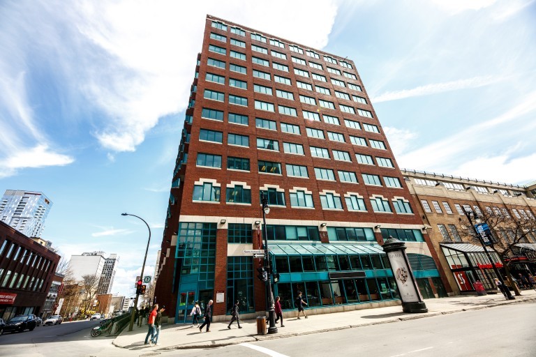 Exterior view of the Faubourg (FB) Building on Ste. Catherine Street West with pedestrians walking nearby.