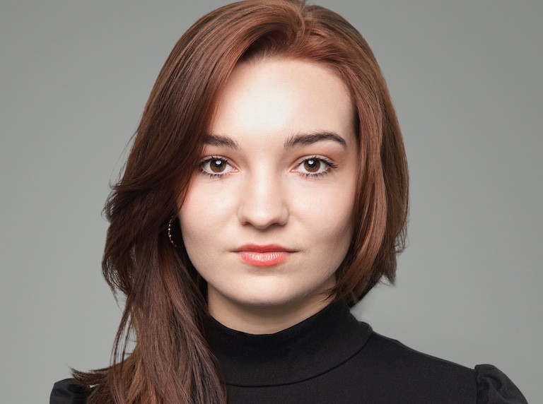 Serious looking young woman with reddish hair wearring a black turtleneck