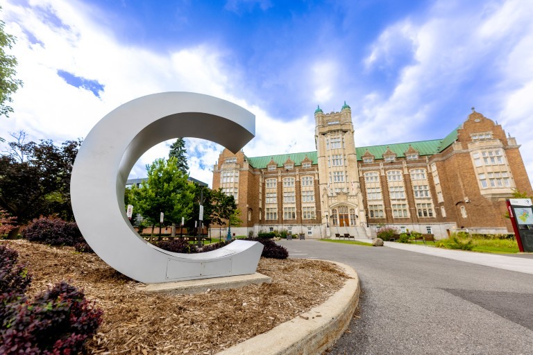 Concordia’s Administration (AD) Building on the Loyola Campus, viewed from the landscaped grounds with a large white C sculpture in the foreground.