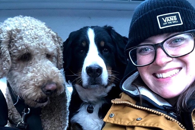 Dogwalker Allison Gautheir, BA 12, in a car with two big dogs in the back seat.