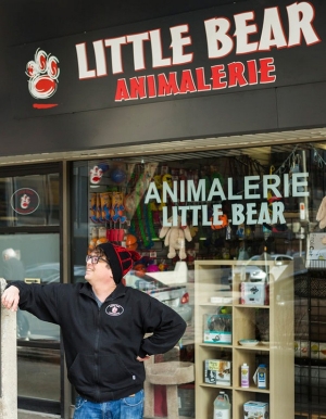 Chuck Altman poses outside his store, resting against the sign