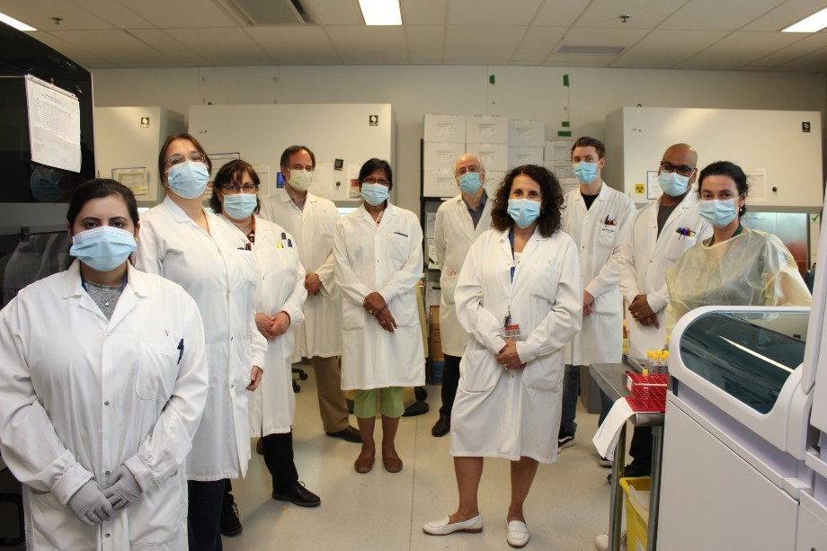 Ten healthcare workers wearing blue masks face the camera.