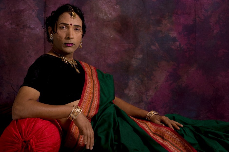 Subject reclining on a sofa dressed in a sari, gazing at the camera defiantly.